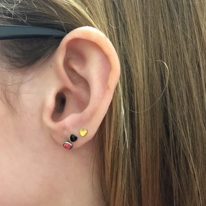 Detailed view of heart studs and opal flat back earrings on ear for multiple piercings