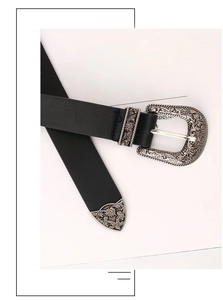Detail of vintage black leather belt with ornate floral carved silver buckle and metal tip