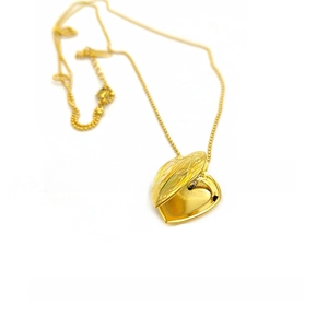 Detailed macro view of an open 18K gold plated heart locket with vintage engravings