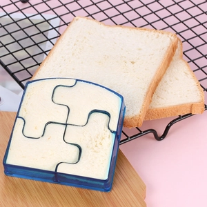 Blue puzzle-shaped sandwich cutter being used to shape bread on a wooden board
