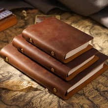 Macro view of stacked vintage brown leather notebooks with snap buttons on an old map