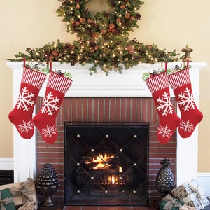 Macro view of four red knitted Christmas stockings with snowflake patterns on fireplace