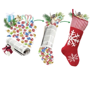 Red knitted Christmas stocking with white snowflakes being filled with holiday gifts and candies