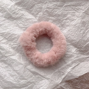 Close-up of soft pink faux rabbit fur scrunchie showing fluffy texture on white paper