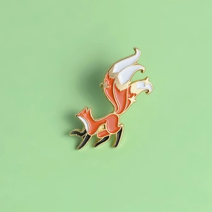 Detailed close-up of a fox enamel brooch pin with orange white and black colors