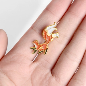 Cute red fox enamel brooch pin with long tail and gold star details on a white background