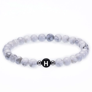 Detail of 6mm white turquoise beaded bracelet with silver spacers and letter H charm