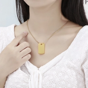 Close-up of golden rectangular pendant necklace on beaded chain worn by a model
