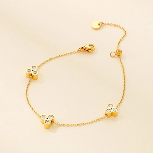 Detail of adjustable gold four-leaf clover bracelet with sparkling inlaid gemstones