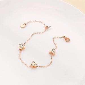 Macro detail of rose gold bracelet featuring three diamond clover elements on white plate