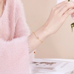 Detail of delicate gold chain bracelet with four-diamond flower charms on a model's wrist