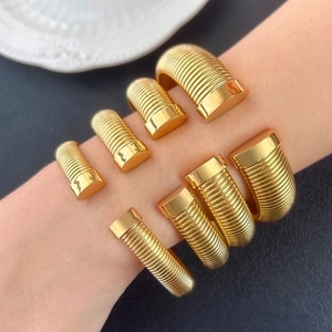 Detail of 18K gold plated stainless steel cuff bracelet with industrial screw texture