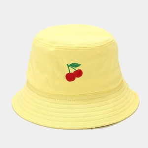 Détail d'un chapeau bob jaune en coton avec broderie de cerises rouges sur le devant de la face