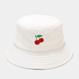 Gros plan d'un bob en coton blanc avec une broderie détaillée de cerise rouge