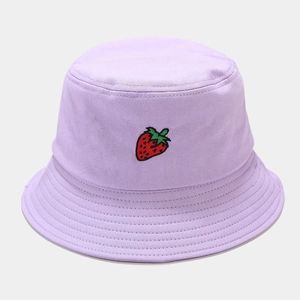 Gros plan d'une broderie fraise sur un bob en coton violet clair avec détails de couture