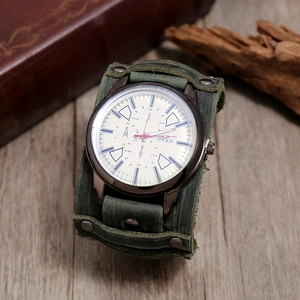 Close-up of a green leather cuff watch on a rustic wood surface with vintage accents