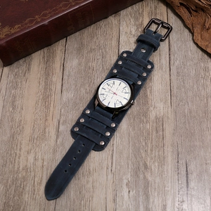 Vintage dark blue leather wide strap watch with metallic studs on wood background