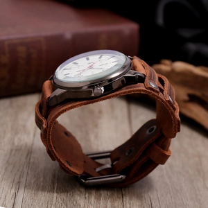Close-up of vintage brown leather cuff watch with metal studs and wide punk style strap