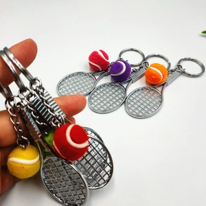 Hand holding colorful felt tennis ball and metal racket keychains in several colors
