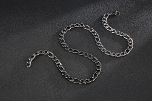 Macro view of a black stainless steel Figaro chain with alternating links on textured background