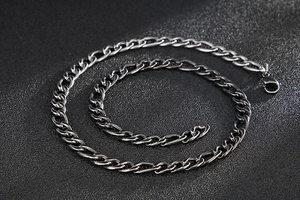 Detail of silver Figaro stainless steel chain with lobster clasp on dark background