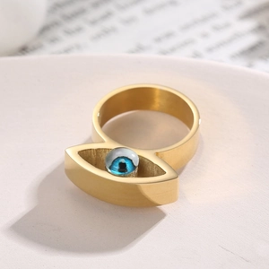 Nahaufnahme eines goldenen Edelstahlrings mit blauem Evil-Eye-Motiv im Hip-Hop-Stil
