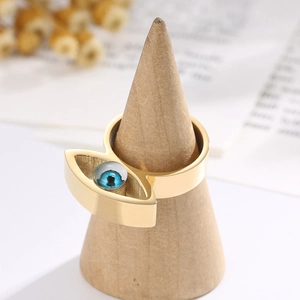 Nahaufnahme eines goldenen Evil Eye Rings mit blauem Edelstein auf einem Holzständer