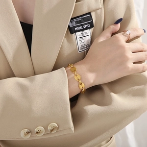 Detailed close-up of a golden coffee bean link bracelet worn on a model wrist