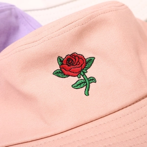 Detailed close-up of red rose embroidery on pink cotton bucket hat with fine stitching