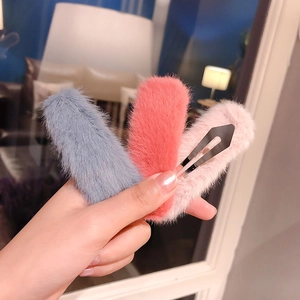 Close-up of three colorful plush hair clips in blue, coral, and pink with metal bases