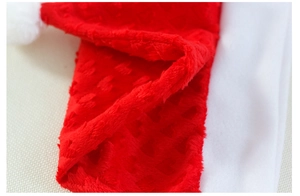 Close-up of red plush Christmas hat fabric featuring embossed heart patterns and white pompom