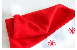 Close-up of red velvet Christmas hat featuring snowflake embroidery and white plush trim