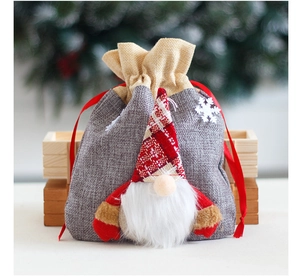 Detail of grey burlap Christmas gift bag with 3D gnome and red drawstring closure