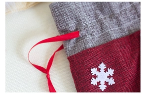 Close-up of linen Christmas gift bag showing red satin drawstring and snowflake detail