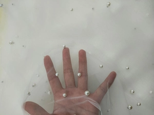 Close-up of translucent white bridal tulle veil with pearls and silver sequins detail