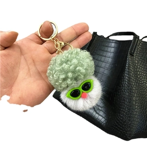 Cute cartoon broccoli plush keychain with green sunglasses on a black leather bag
