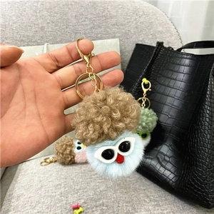 Cute plush cauliflower doll keychain with blue body and white sunglasses on black bag