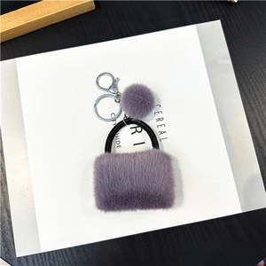 Detail shot of a purple plush handbag keychain with silver metal ring on a book