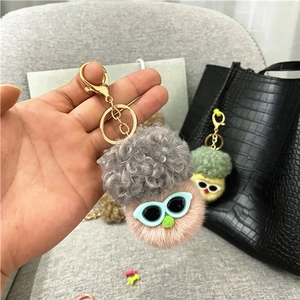 Close-up of pink cauliflower plush keychain with grey hair and blue glasses on a bag
