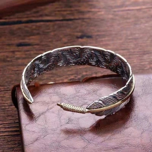 Macro shot of silver and gold feather cuff bracelet with detailed texture on leather