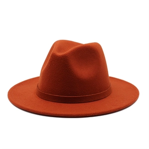 Detailed texture of orange wool felt fedora hat with matching decorative band on white background