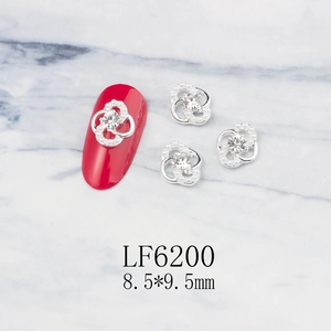 Detailed view of silver hollow flower nail charms with pearls on red manicured nails