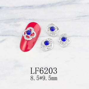 Detail of silver clover nail charms with blue center stone and white diamonds