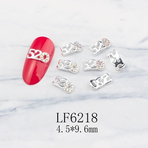 Detailed view of silver 520 nail charm with iridescent rhinestones on red fake nail