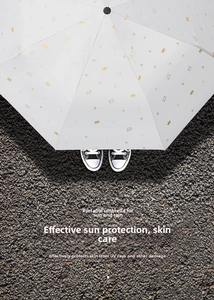 Detail of light grey umbrella with gold crown prints on grey asphalt background