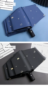 Detail of navy and black automatic folding umbrellas with gold crown and floral patterns
