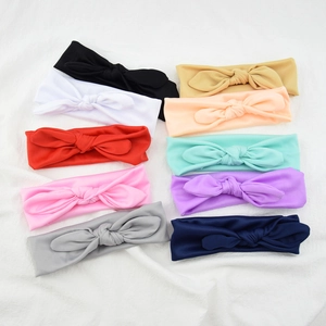 Detailed flat lay of ten colorful knotted baby headbands with soft fabric bows