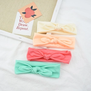 Close-up of four colored elastic knotted bow headbands for babies in a soft knitted fabric