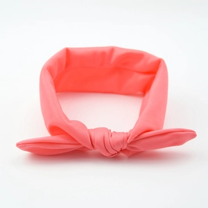 Pink knotted baby headband with elastic rabbit ears on a clean white background