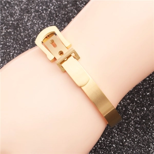 Detail of gold belt buckle bangle with brushed metal finish on a wrist model
